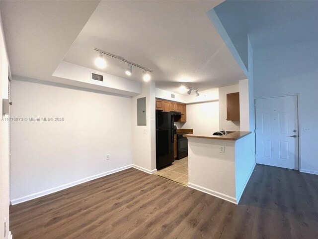 kitchen with electric panel, freestanding refrigerator, wood finished floors, baseboards, and visible vents