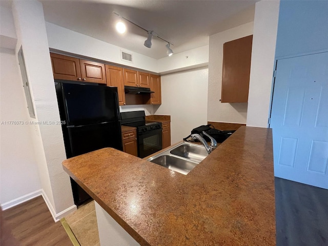 kitchen with under cabinet range hood, a sink, visible vents, a peninsula, and black appliances