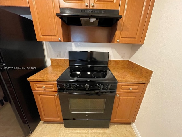 kitchen featuring black appliances, under cabinet range hood, and brown cabinets