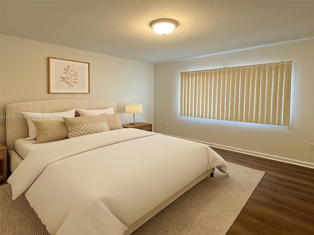 bedroom featuring baseboards, wood finished floors, and a textured ceiling