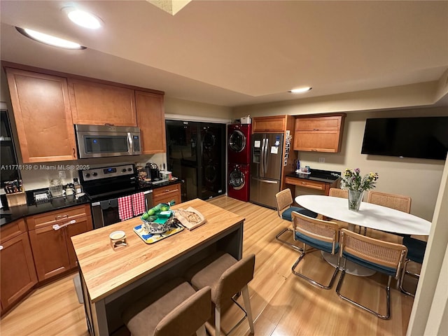 400 Valencia Ave Unit 2, Coral Gables, FL 33134 - kitchen featuring appliances with stainless steel finishes, stacked washing machine and dryer, light wood-style flooring, a kitchen breakfast bar, and butcher block counters