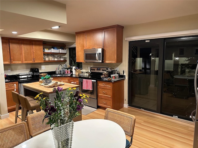 400 Valencia Ave Unit 2, Coral Gables, FL 33134 - kitchen with appliances with stainless steel finishes, light wood-style floors, open shelves, brown cabinetry, and a sink