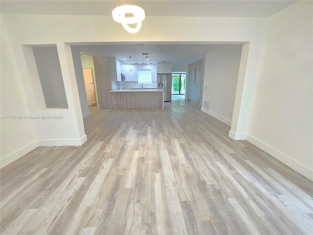 unfurnished living room with baseboards and light wood-type flooring
