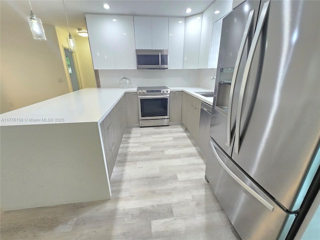 kitchen featuring light countertops, a peninsula, stainless steel appliances, and modern cabinets