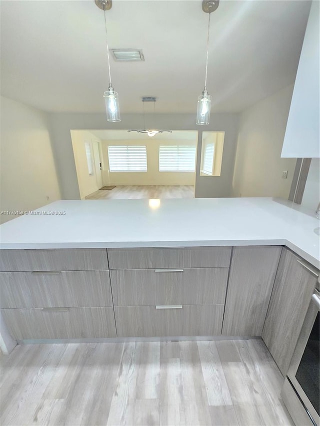 kitchen featuring hanging light fixtures, gray cabinetry, light countertops, and modern cabinets