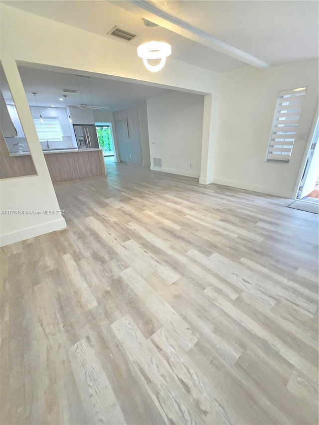 unfurnished living room with baseboards, light wood-style floors, and visible vents