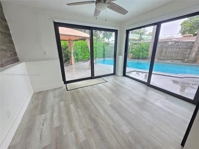 empty room with baseboards, wood finished floors, a healthy amount of sunlight, and a ceiling fan