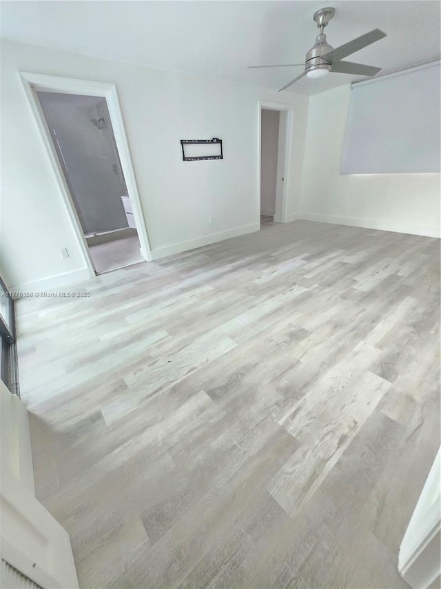 empty room featuring baseboards, light wood-type flooring, and ceiling fan