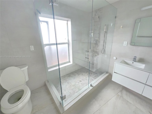full bath with toilet, vanity, a shower stall, tile patterned flooring, and tile walls