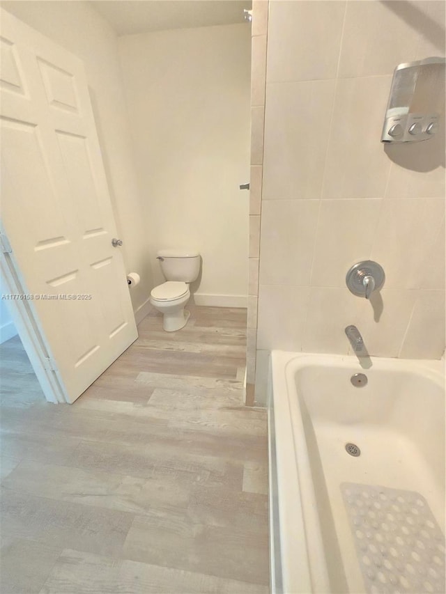 full bathroom with baseboards, wood finished floors, and toilet