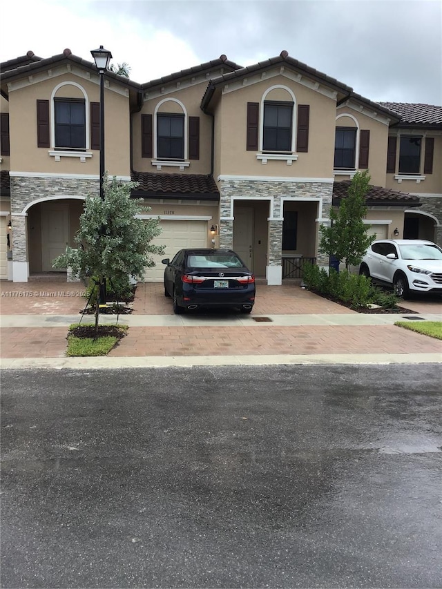 11378 SW 254th Ter, Homestead, FL 33032 - view of property featuring stone siding, a tile roof, decorative driveway, and an attached garage