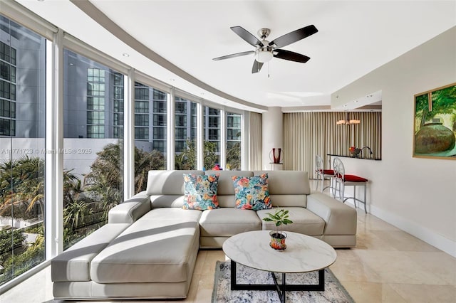 living room with a wealth of natural light, expansive windows, ceiling fan, and baseboards