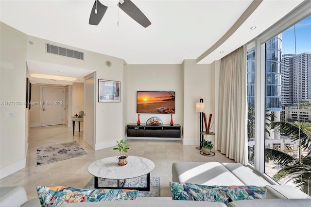 tiled living area with baseboards, expansive windows, visible vents, and a ceiling fan