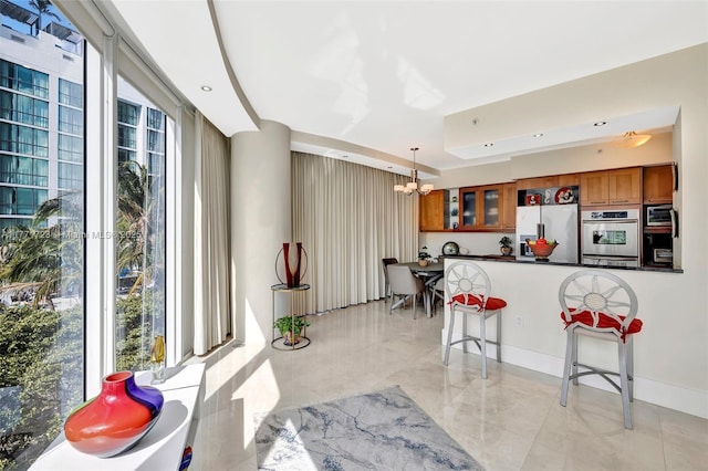 333 Las Olas Way Unit 1007, Fort Lauderdale, FL 33301 - kitchen with brown cabinetry, stainless steel appliances, a chandelier, a breakfast bar area, and dark countertops