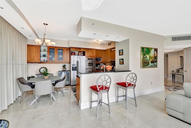 kitchen with visible vents, stainless steel appliances, brown cabinetry, and a peninsula