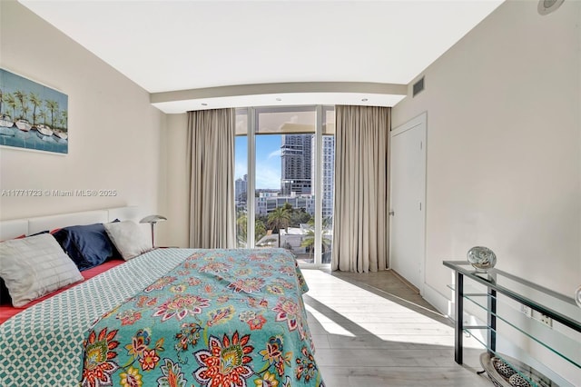 bedroom with access to exterior, visible vents, and wood finished floors