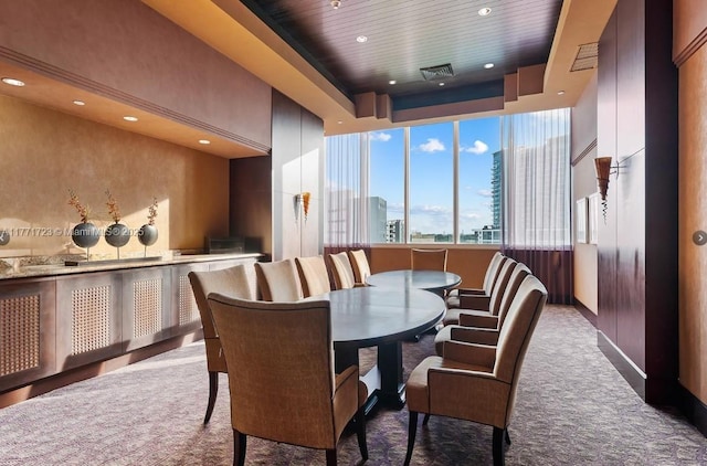 carpeted dining space with a tray ceiling, wood ceiling, visible vents, a view of city, and recessed lighting