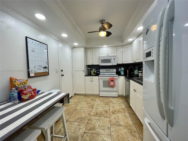 kitchen featuring white appliances, a tray ceiling, tasteful backsplash, white cabinetry, and ornamental molding