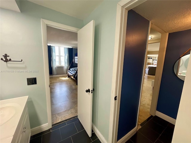 bathroom featuring tile patterned flooring, vanity, baseboards, and a textured ceiling