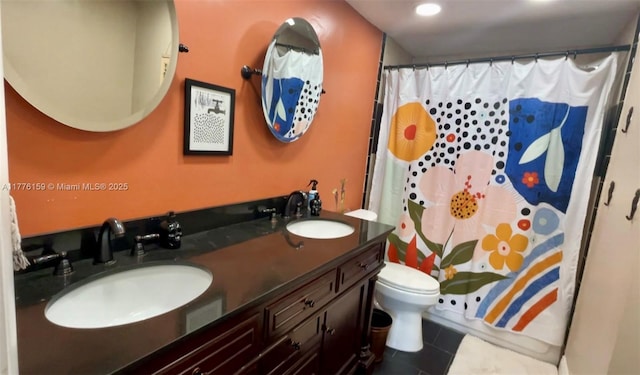 full bathroom featuring tile patterned flooring, double vanity, a sink, and toilet