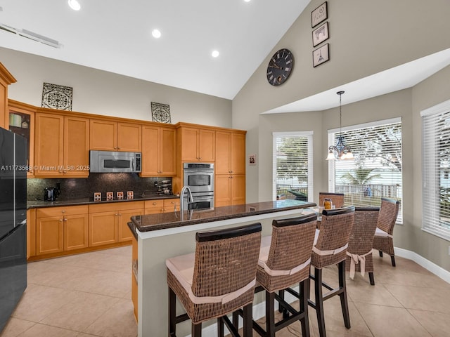 17794 SW 47th St, Miramar, FL 33029 - kitchen with appliances with stainless steel finishes, high vaulted ceiling, tasteful backsplash, light tile patterned floors, and a kitchen breakfast bar