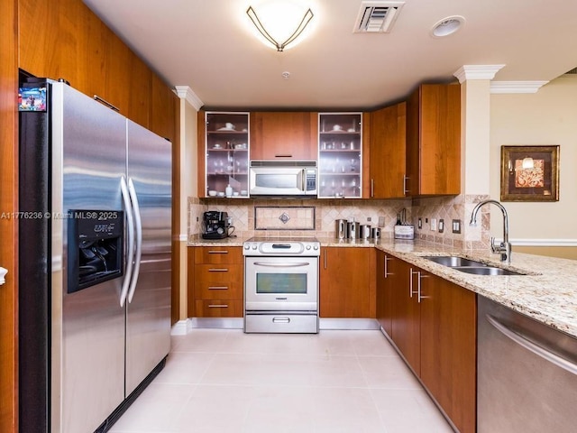 kitchen featuring a sink, visible vents, appliances with stainless steel finishes, brown cabinetry, and ornamental molding