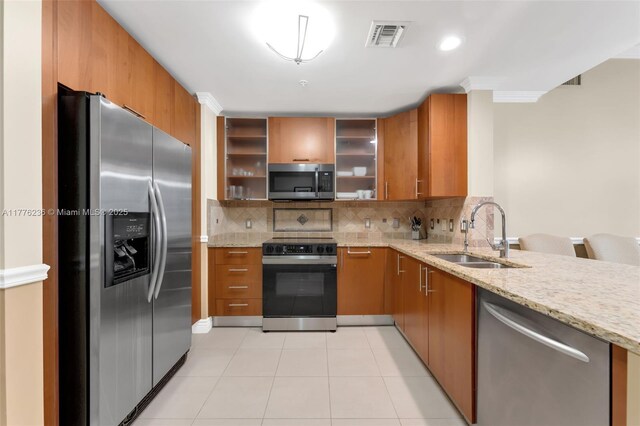 1945 S Ocean Dr Unit 604, Hallandale Beach, FL 33009 - kitchen featuring stainless steel appliances, brown cabinets, light stone countertops, and crown molding