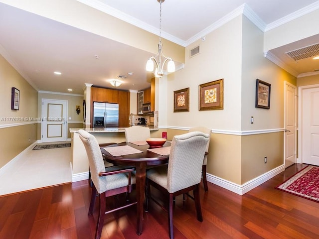 dining room with visible vents, wood finished floors, a chandelier, and ornamental molding