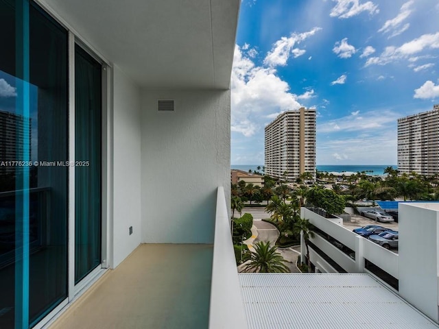 balcony featuring visible vents, a water view, and a view of city