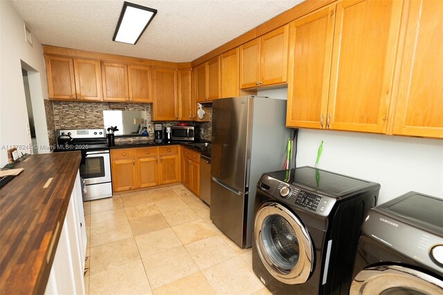 2700 Casita Way Unit 2150, Delray Beach, FL 33445 - kitchen with appliances with stainless steel finishes, wood counters, washer / dryer, backsplash, and a textured ceiling