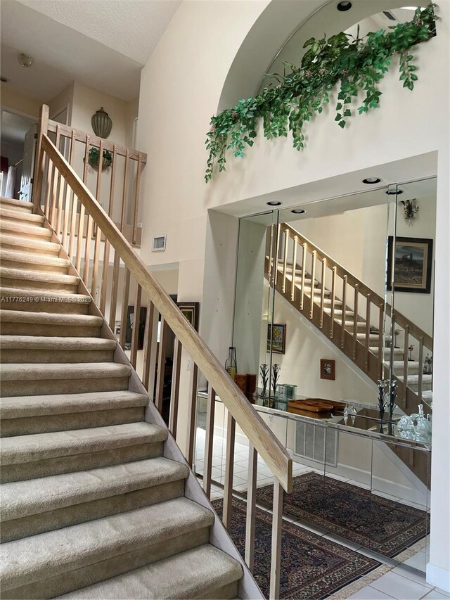 721 Spring Lake Dr, Melbourne, FL 32940 - staircase with tile patterned floors, visible vents, and a high ceiling