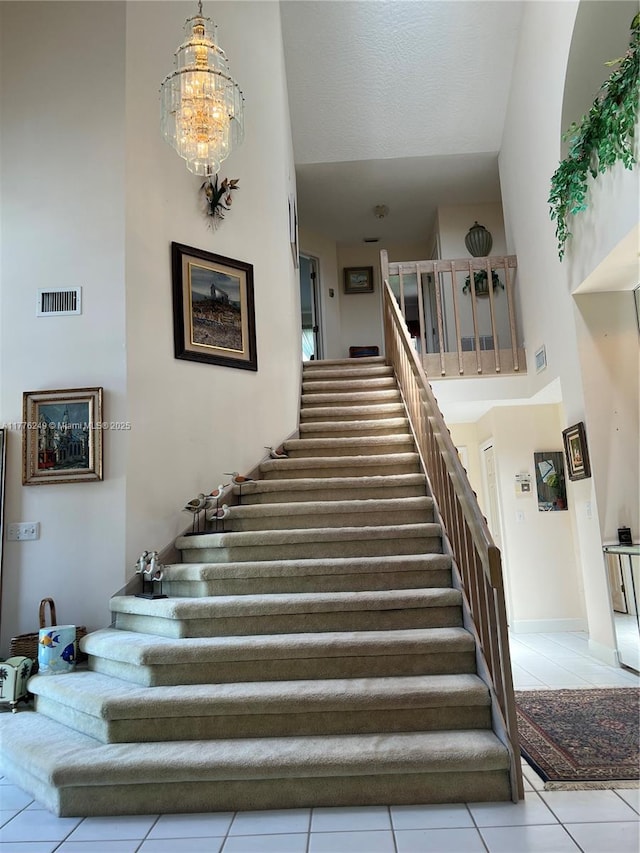 721 Spring Lake Dr, Melbourne, FL 32940 - staircase with tile patterned floors, a towering ceiling, visible vents, and a notable chandelier