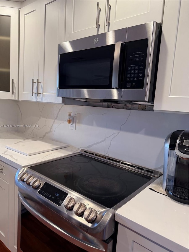 2912 NW 80th Ave, Sunrise, FL 33322 - kitchen with backsplash, white cabinetry, light stone counters, and stainless steel appliances