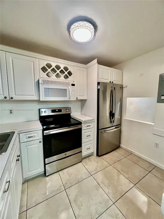 kitchen with light countertops, appliances with stainless steel finishes, white cabinetry, and light tile patterned floors