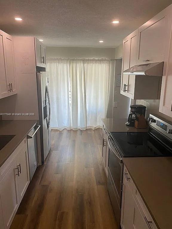 6342 W Longboat Ln W Unit C201, Boca Raton, FL 33433 - kitchen with appliances with stainless steel finishes, under cabinet range hood, white cabinetry, dark wood-type flooring, and recessed lighting