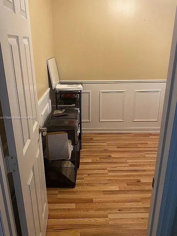 interior space with light wood-style flooring, a decorative wall, and wainscoting