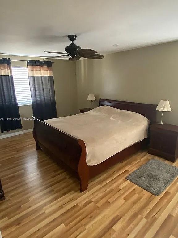 bedroom with wood finished floors, baseboards, and a ceiling fan