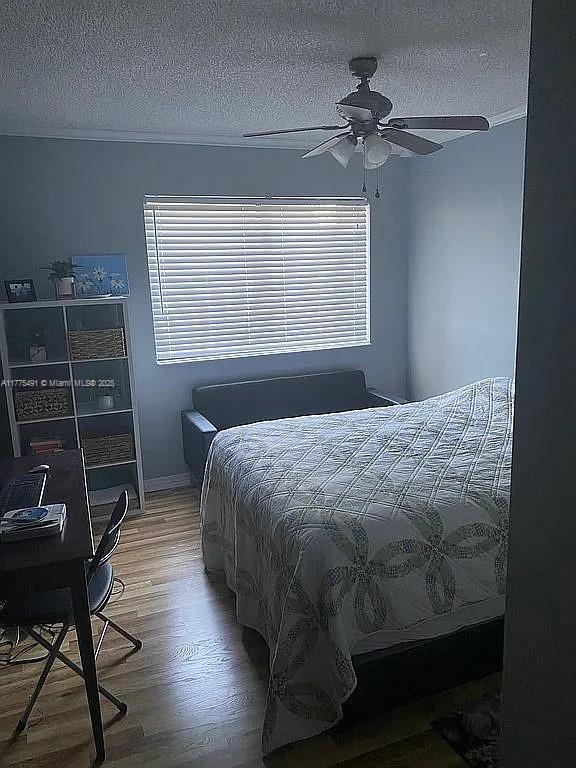 bedroom featuring a textured ceiling, wood finished floors, and a ceiling fan