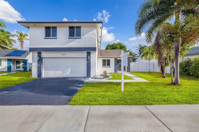 traditional-style house featuring a garage, stucco siding, aphalt driveway, and a front lawn
