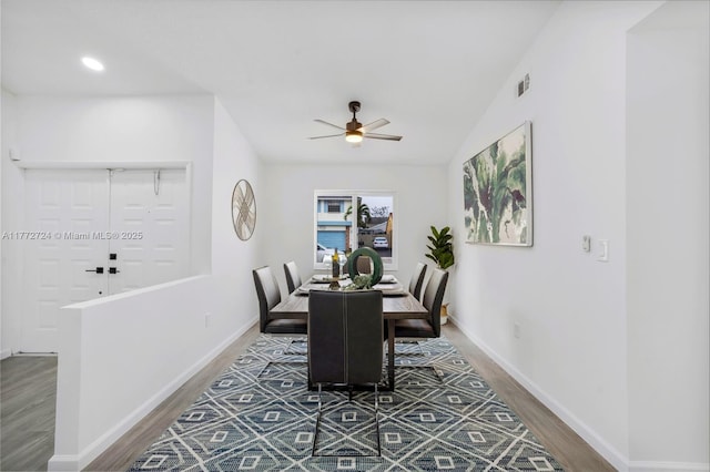 dining space featuring vaulted ceiling, wood finished floors, baseboards, visible vents, and ceiling fan