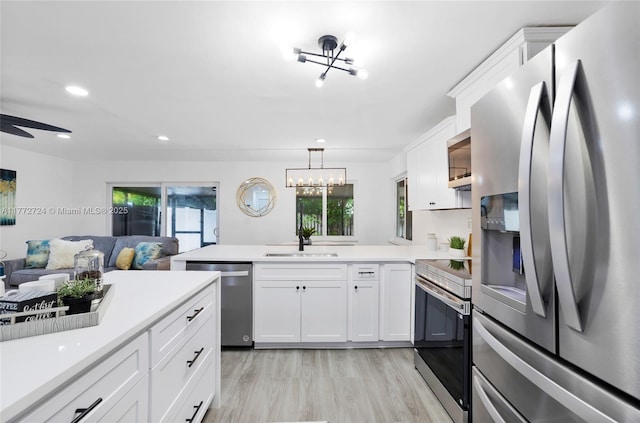 kitchen with a wealth of natural light, a sink, appliances with stainless steel finishes, a peninsula, and open floor plan
