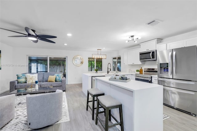 kitchen featuring white cabinets, visible vents, light countertops, a peninsula, and stainless steel appliances