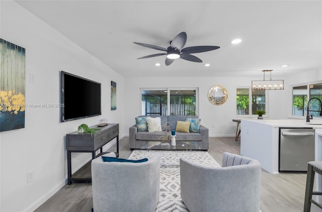 living area featuring ceiling fan with notable chandelier, light wood-style floors, and recessed lighting