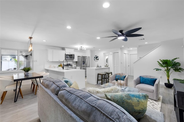 living area with visible vents, light wood-style flooring, and ceiling fan