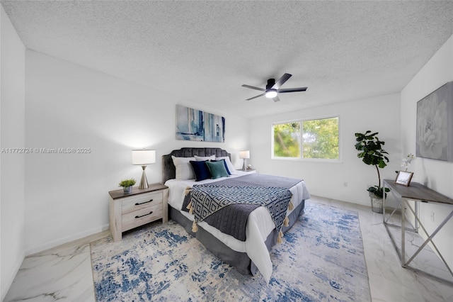 bedroom featuring marble finish floor, baseboards, a ceiling fan, and a textured ceiling