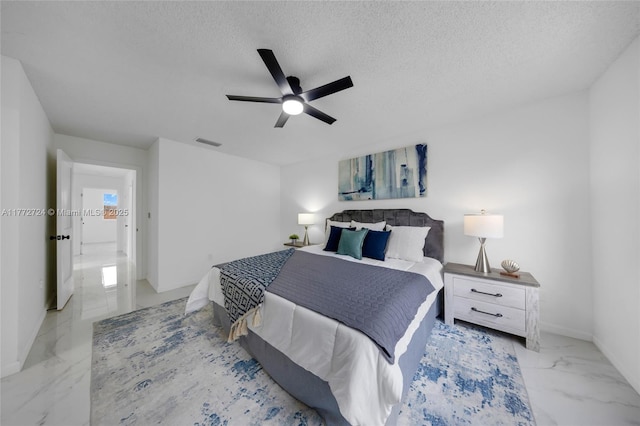 bedroom with marble finish floor, a textured ceiling, ceiling fan, and visible vents