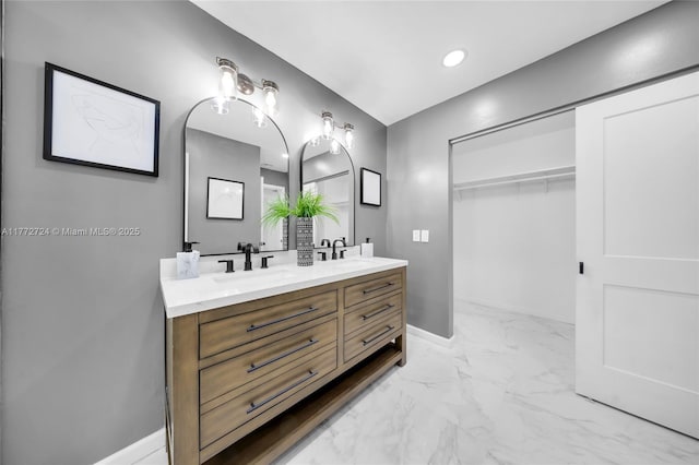 bathroom featuring baseboards, marble finish floor, a sink, and double vanity
