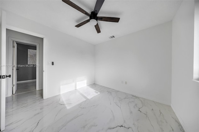 empty room with marble finish floor, visible vents, and ceiling fan