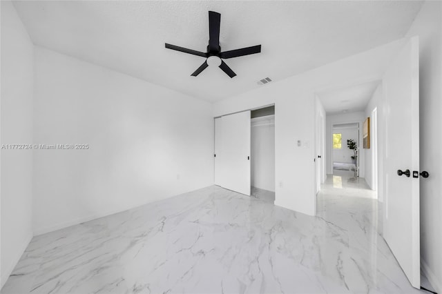 unfurnished bedroom featuring a closet, a textured ceiling, marble finish floor, visible vents, and ceiling fan