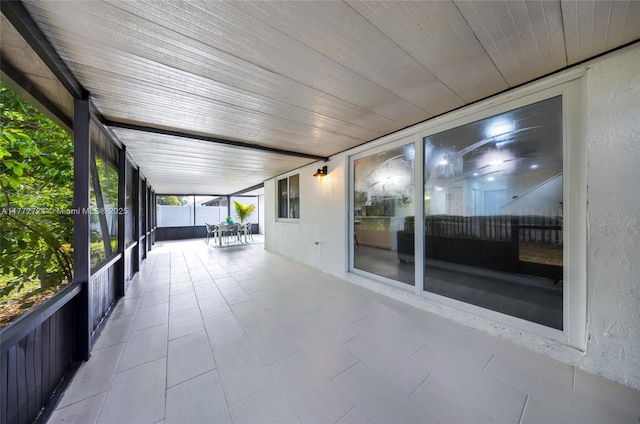 unfurnished sunroom with wooden ceiling, tile patterned floors, and a textured wall